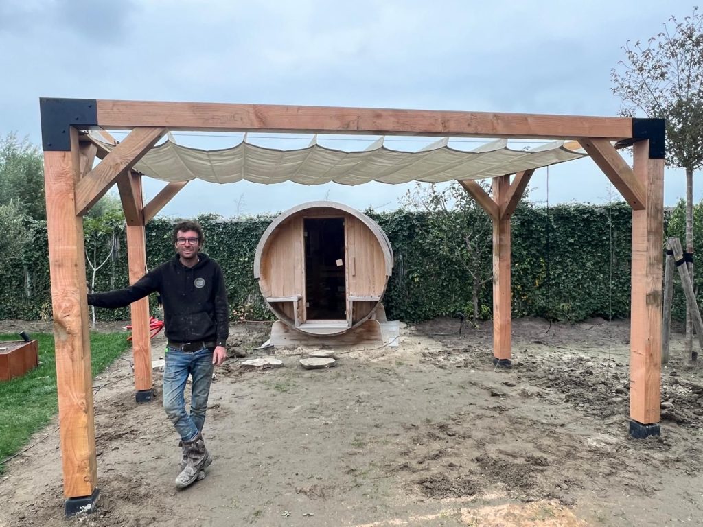 Michael Wouterse bij een zelfgebouwde houten overkapping